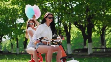 Tatlı sexy girls kısa şort binmek bir elektrikli scooter parkta pamuk.