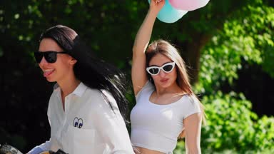 İki genç ve seksi esmer arkadaşı ile saç kısa denim şort birbirlerine sarılma tadını güneşli bir günde parkta bir elektrikli motosiklet Binme gevşek. Arkadaşlarım birlikte vakit