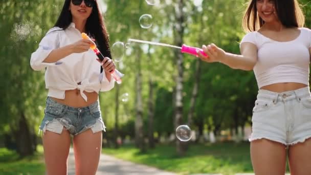 Twee mooie jonge meisjes in sexy kleding zijn lachen en dansen tijdens het rijden een Segway in het Park in het weekend spelen met zeepbellen in slow motion — Stockvideo