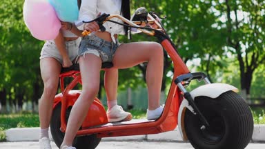 Tatlı sexy girls kısa şort binmek bir elektrikli scooter parkta pamuk.