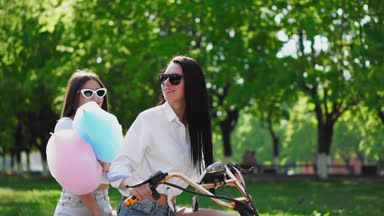 İki güzel kız kot şort parkta bir elektrikli motorla yaz aylarında binmek