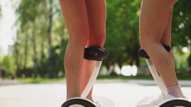 Genç kızların güzel ince tion kısacası chertah portre üzerinde beyaz gyrometer elektrik Segway binmek parkta.
