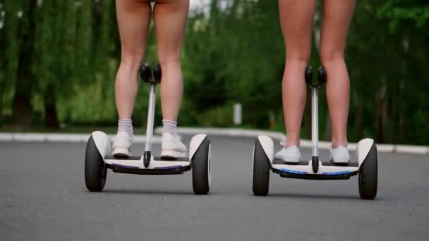 Close-up vista das pernas traseiras das meninas em shorts curtos montando GyroScooter em um dia ensolarado de verão — Vídeo de Stock