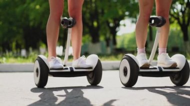 Arka bacaklar kısa şortlu kız yakından görmek Gyroscooter binmek. İki kız arkadaşım parkta binmek