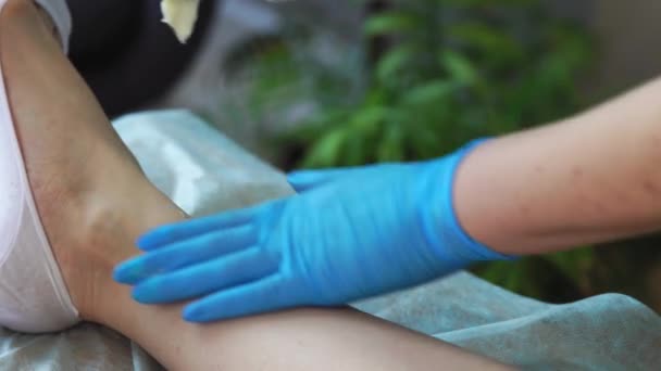 Close-up of the hand in rubber gloves is applied to the hair removal paste and by special technology shugaring removes hair — Stock Video