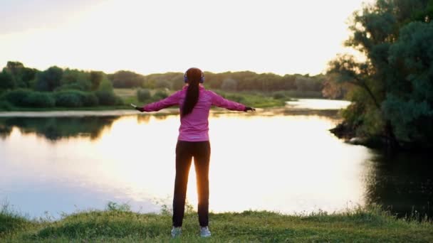 The girl warms up early in the morning before training preparing for a run in the sun — Stock Video