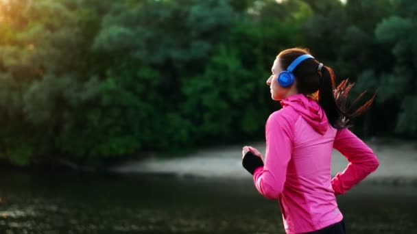 Ein morgendliches Joggen im Park in der Nähe des Teiches in den sonnigen Sonnenstrahlen der Morgendämmerung, bereitet sich das Mädchen auf Mariano und führen einen gesunden Lebensstil — Stockvideo