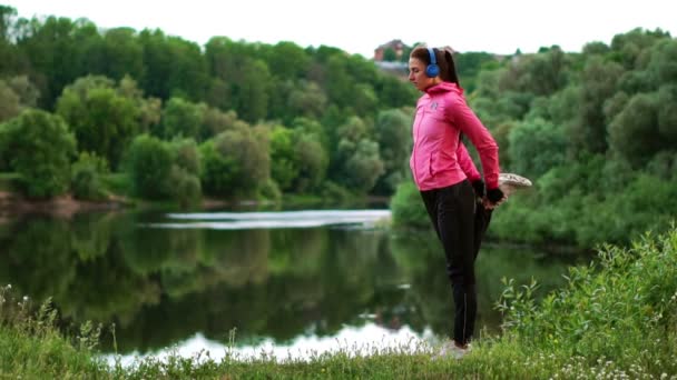 La niña se calienta temprano en la mañana antes de entrenar preparándose para una carrera al sol — Vídeo de stock