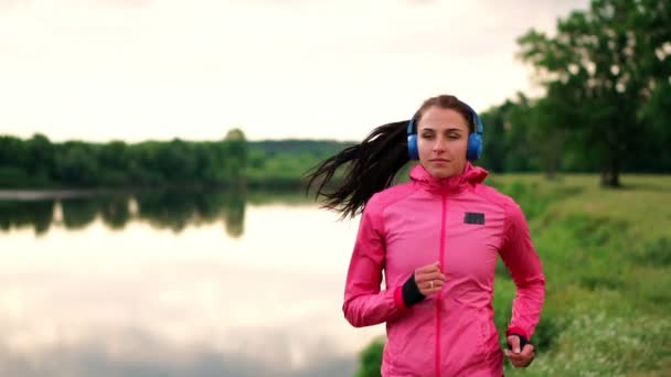 Ráno jog v parku u rybníka v sluneční paprsky úsvitu, dívka se připravuje na Mariano a vést zdravý životní styl — Stock video