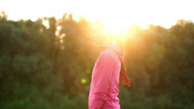 Pembe bir ceket, bir kız için bir çalışma sıcak kadar hazırlanıyor ve kulaklık telefon aracılığıyla müzik dinle