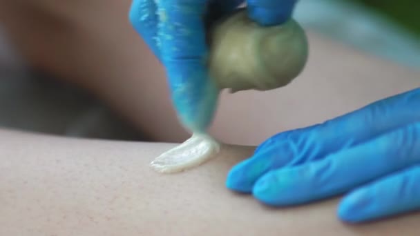 Nahaufnahme im Schönheitssalon Meister in Handschuhen macht den Vorgang, um die Haare an den Beinen mit einer Zuckermischung entfernen — Stockvideo