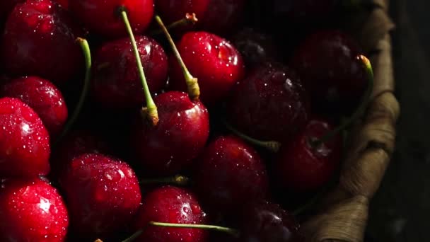 Cerises douces mûres rouges gros plan avec des gouttes d'eau dans le panier sur l'herbe — Video