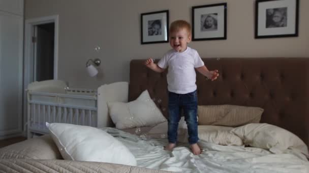 Glückssprünge auf dem Bett beim Anblick fliegender Seifenblasen — Stockvideo