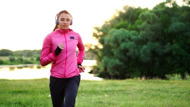 Poranny jogging w parku, w pobliżu stawu w promienie słoneczne świt, Dziewczyna przygotowuje się do Mariano i prowadzić zdrowy styl życia — Wideo stockowe