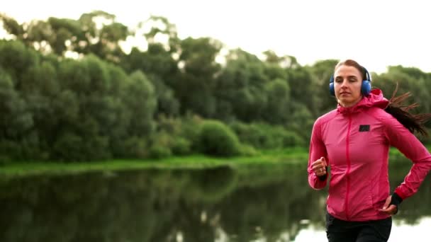 Una mañana trotar en el parque cerca del estanque en los rayos soleados del amanecer, la chica se está preparando para Mariano y llevar un estilo de vida saludable — Vídeos de Stock