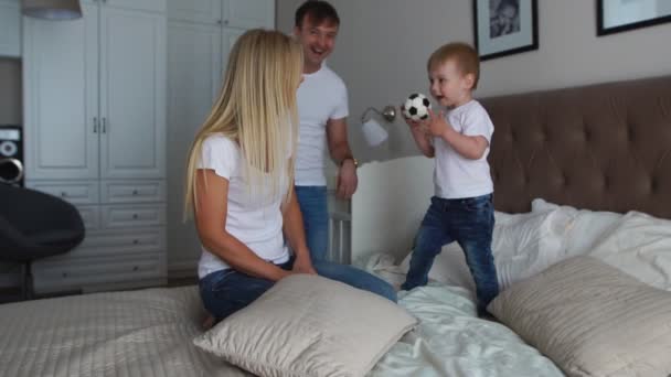 親のベッドの上の彼らの幼い娘を楽しんでします。朝の時間を過ごす家族 — ストック動画