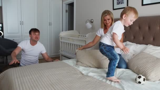 Família feliz jogando a travesseiros luta na cama em casa — Vídeo de Stock