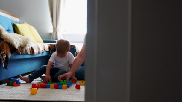 Boldog családi apa-anya és a baba 2 év játék lego a világos nappaliban. Lassú mozgású felvétel boldog család — Stock videók