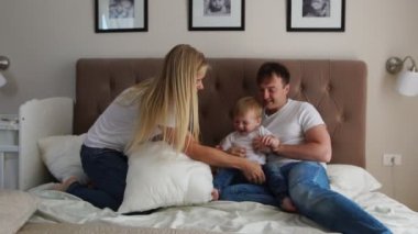Sevgi dolu anne gülerek ve gülümseyerek yatak odasında yatağın oğulları ile oynamak