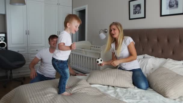 Ouders met plezier met hun dochtertje op bed. Familie doorbrengen van tijd in de ochtend — Stockvideo