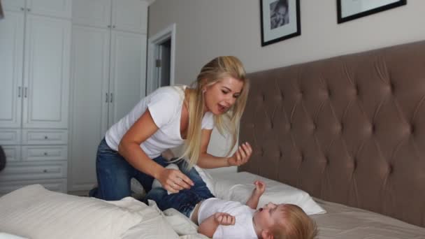 Mamá y papá le hacen cosquillas a su hijo. personas, familia, diversión y concepto de la mañana - niño feliz con los padres cosquillas en la cama en casa. Familia feliz pasando tiempo juntos en la hora de acostarse jugando y abrazándose — Vídeos de Stock