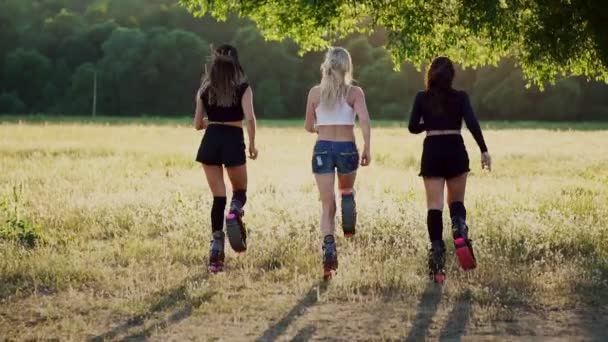 Tres chicas en botas con primaveras corriendo por el parque de verano al atardecer haciendo deporte — Vídeo de stock