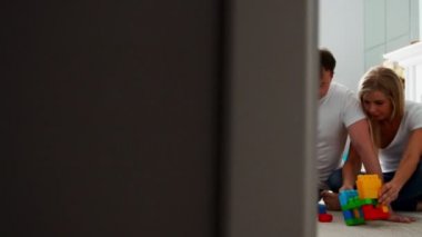 Mutlu aile baba anne ve bebek 2 yıl onların parlak oturma odasında lego oynarken. Ağır çekim mutlu aile çekim