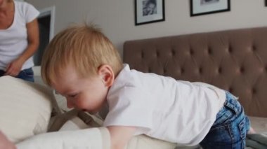 Genç Anne ve babası onun 2 yıl eski küçük oğlu pijama giymiş ile rahatlatıcı ve oynarken yatak birlikte hafta sonları, tembel sabah, sıcak ve rahat sahne. Pastel renkler, seçici