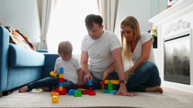 Mutlu aile baba anne ve bebek 2 yıl onların parlak oturma odasında lego oynarken. Ağır çekim mutlu aile çekim