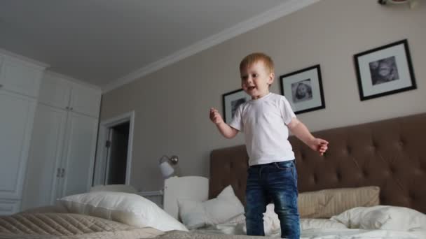 Saltando de felicidade na cama olhando para bolhas de sabão voador — Vídeo de Stock