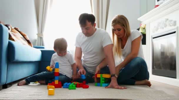 Щаслива родина тато мама і дитина 2 роки грають в лего у своїй світлій вітальні. Стрілянина повільного руху щаслива сім'я — стокове відео