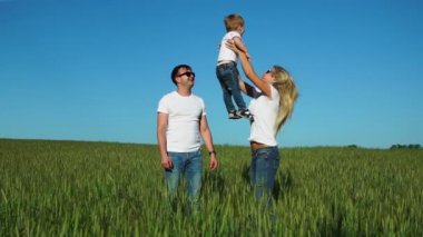 Mutlu bir aile: babası anne ve oğlu atlamak ve gülmek beyaz t-shirt ve jeans giymiş alanında
