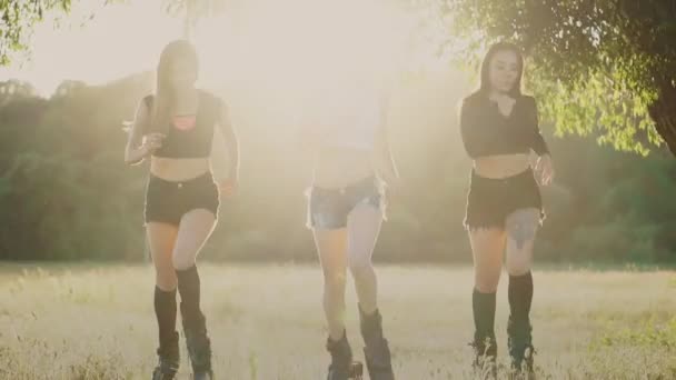 Três meninas de botas com molas correndo pelo parque de verão ao pôr do sol fazendo esportes — Vídeo de Stock