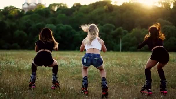 Formation de groupe kangoo. Trois filles au coucher du soleil exécutent des squats dynamiques visant à amincir et renforcer les muscles des cuisses — Video