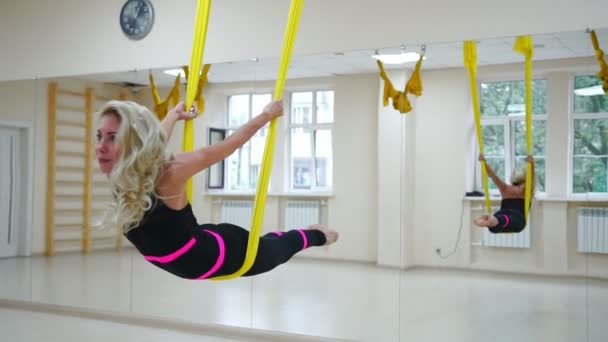 Das Mädchen macht im weißen Studio Aero Yoga und fliegt in Zeitlupe über den Boden auf den Leinwänden — Stockvideo