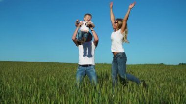 Mutlu bir aile: babası anne ve oğlu atlamak ve gülmek beyaz t-shirt ve jeans giymiş alanında