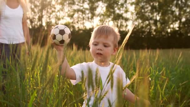 Fiú-fehér inget, sétál a mező közvetlenül a kamerába, és mosolyog, tüskék területén — Stock videók