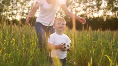 Mutlu bir aile kavramı. Kameranın arkasında anne standları bakarak güneş batan güneşin alanında karşısında çocuk çavdar alanına yürüyor