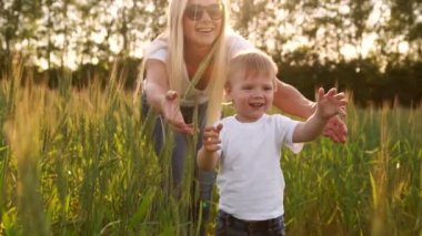 Mutlu bir aile kavramı. Kameranın arkasında anne standları bakarak güneş batan güneşin alanında karşısında çocuk çavdar alanına yürüyor