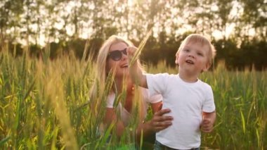 Mutlu bir aile kavramı. Çavdar alanında, çocuk ve annesi birbirlerine arka ışık spikelets içinde gülümseyen sever misiniz