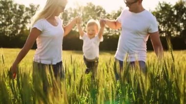 Spikelets bir çocuk onun gülen silah ve gülümsüyor mutluluk ile sallanan buğday ile bir alanda çalışan bir genç çocuk ile genç bir aile