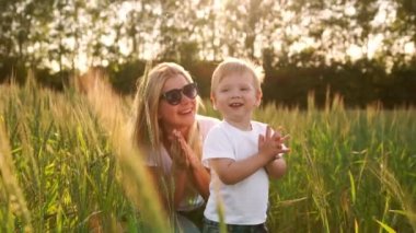 Mutlu bir aile kavramı. Çavdar alanında, çocuk ve annesi birbirlerine arka ışık spikelets içinde gülümseyen sever misiniz