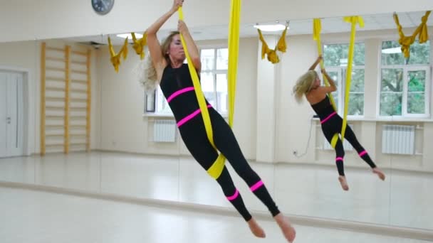 Fly Jóga v bílé tělocvičně. Gymnastice provádí fyzické cvičení pro fly jóga, pilates, obnovující zdraví — Stock video