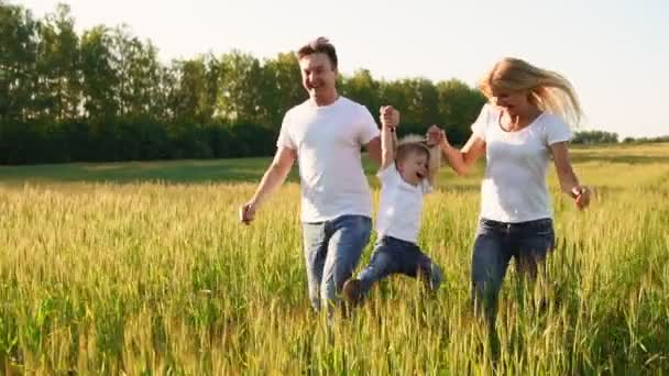 Glückliche Familie: Vater, Mutter und Sohn laufen in weißen T-Shirts auf das Feld — Stockvideo