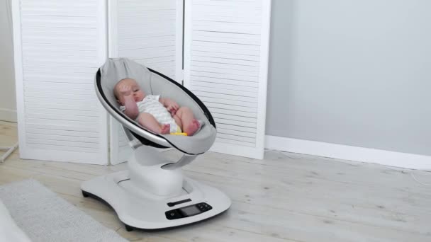 Cadeira de balanço de alta tecnologia moderna ajuda os pais a colocar a criança na cama. Interior branco do quarto das crianças — Vídeo de Stock