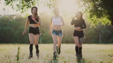 Yaz parkta spor yaparken günbatımında çalışan yaylar ile Çizmeli üç kız