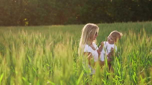 Mutlu bir aile eğleniyor. Kahverengi kıvırcık saçlı ve kızıl saçlarını yukarı birbirine gösterilen annesiyle bebek çocuk. Açık atış — Stok video
