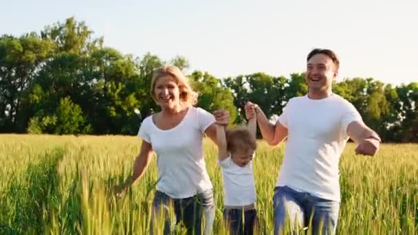 Familia feliz, mamá papá e hijo en un paseo emocional. Correr y disfrutar de la vida en un campo verde al aire libre, cielo azul, naturaleza — Vídeos de Stock