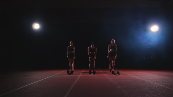 Жіночі бігуни легкої атлетики відстежують присідання на стартових блоках перед гонкою. У повільному русі . — стокове відео