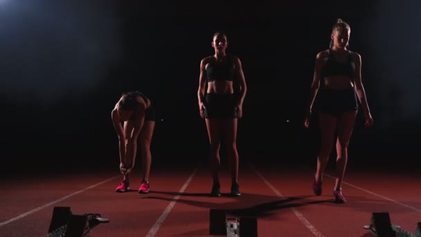 Corredoras en pista de atletismo agachándose en los bloques de salida antes de una carrera. En cámara lenta . — Vídeo de stock